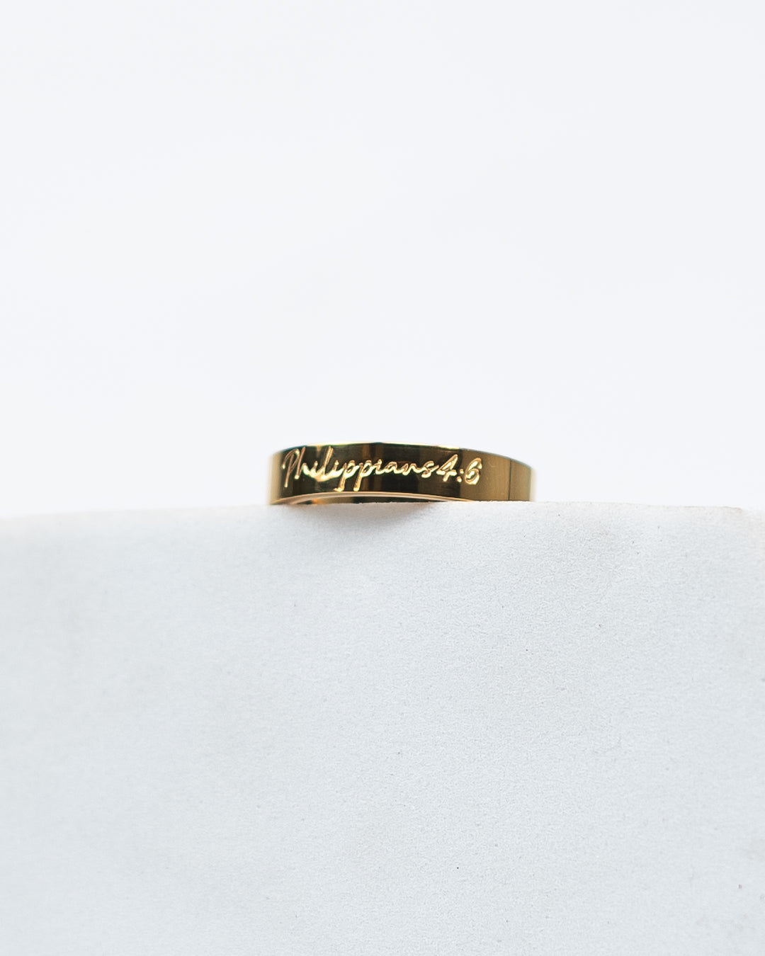 Gold ring with 'Philippians 4:6' engraving on a white background